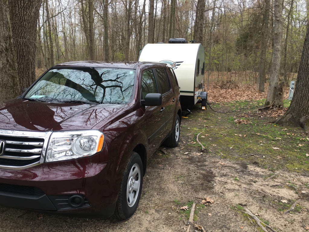 A car parked on pavement near a forest

Description automatically generated